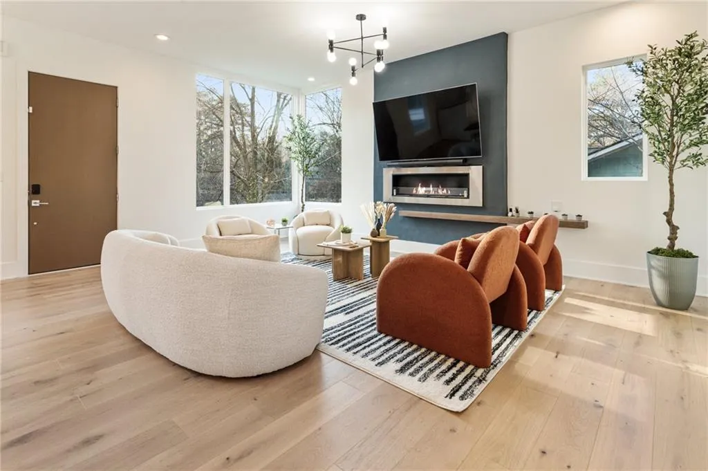 Living room with wood finished floors, a chandelier, recessed lighting, baseboards, and a large fireplace