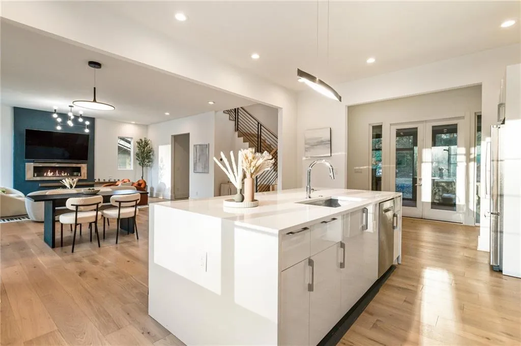 Kitchen with white cabinetry, hanging light fixtures, a sink, light wood-style floors, and recessed lighting