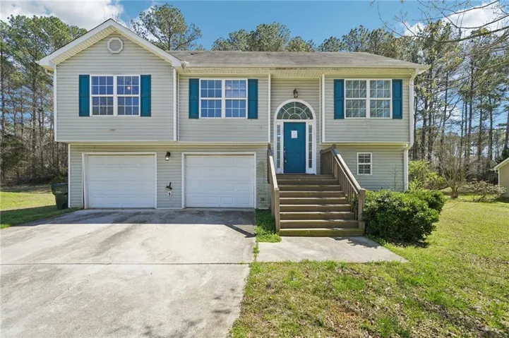 Raised ranch with a front yard, concrete driveway, and a garage