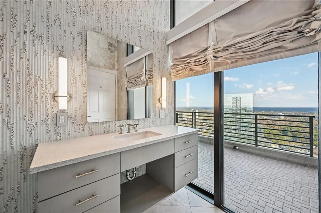Bathroom featuring wallpapered walls, vanity, light tile patterned flooring, and a city view