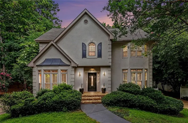 Stucco exterior residence featuring a prominent gabled roofline