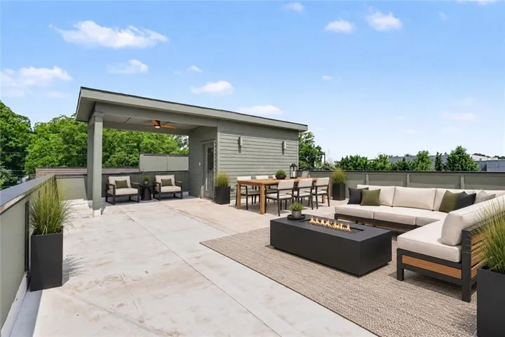 Expansive rooftop deck featuring a covered lounge area with ceiling fan, dining space, and a fire pit