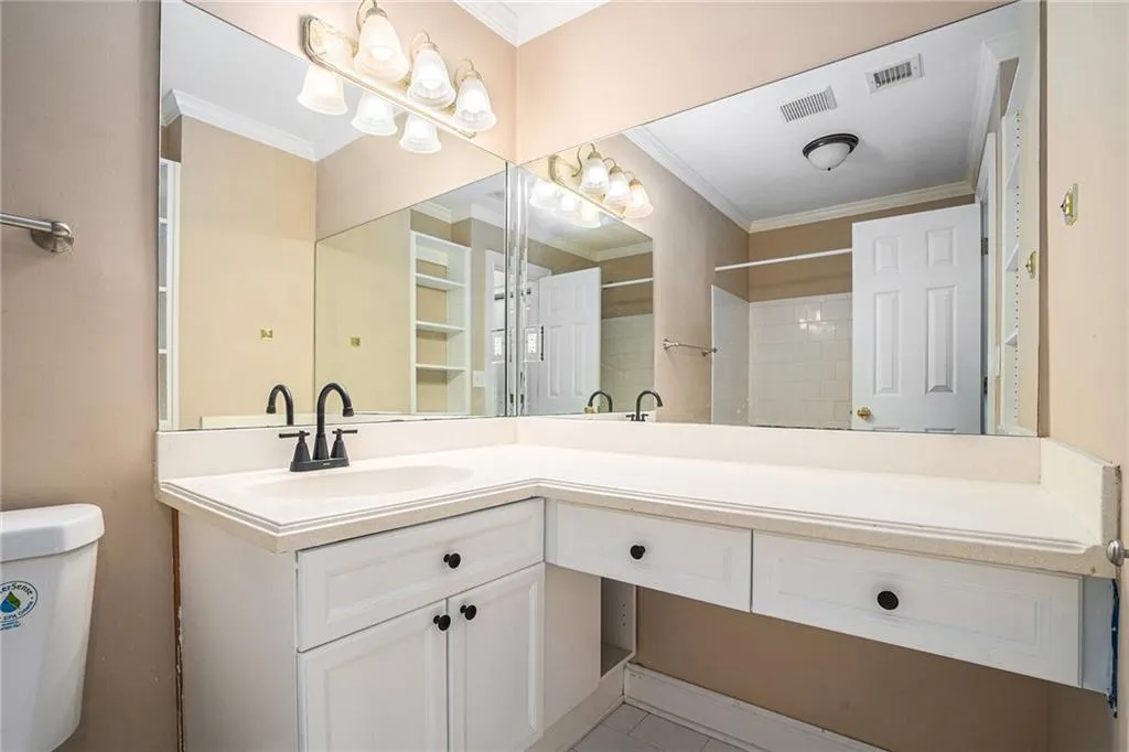 Bathroom featuring vanity, crown molding, tile patterned flooring, and toilet