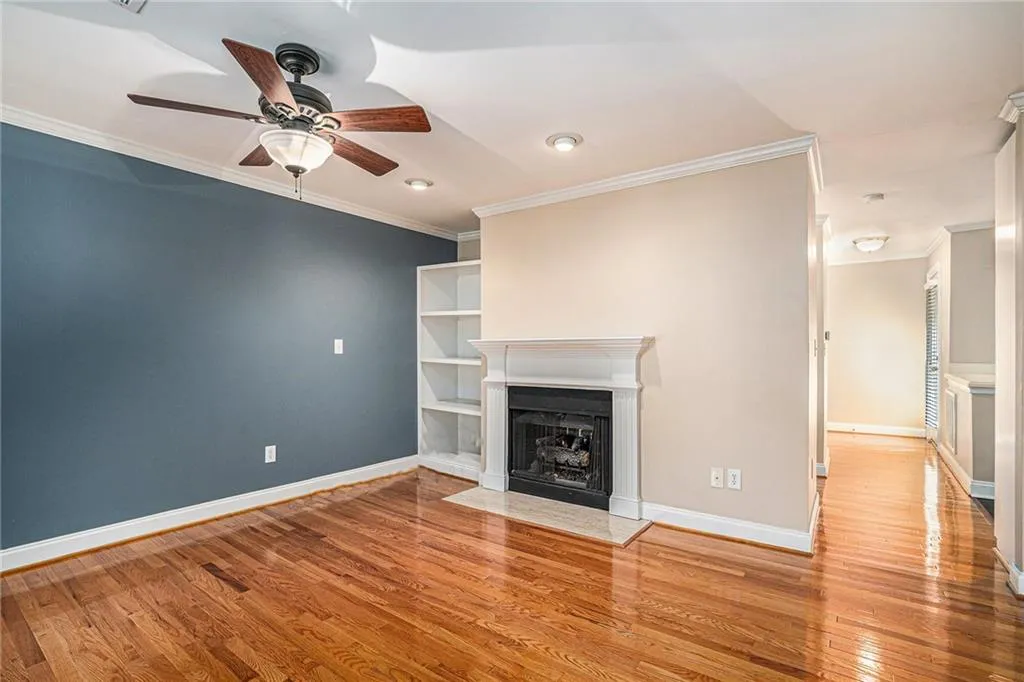 Unfurnished living room featuring crown molding, ceiling fan, and wood-type flooring