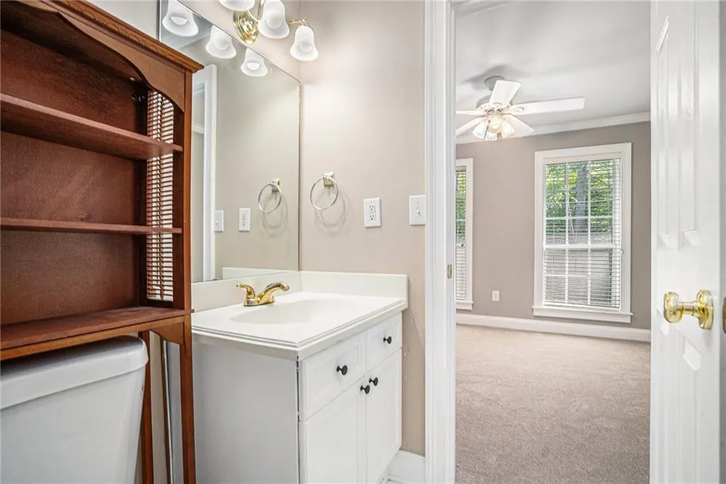 Bathroom with ornamental molding, vanity, ceiling fan, and toilet