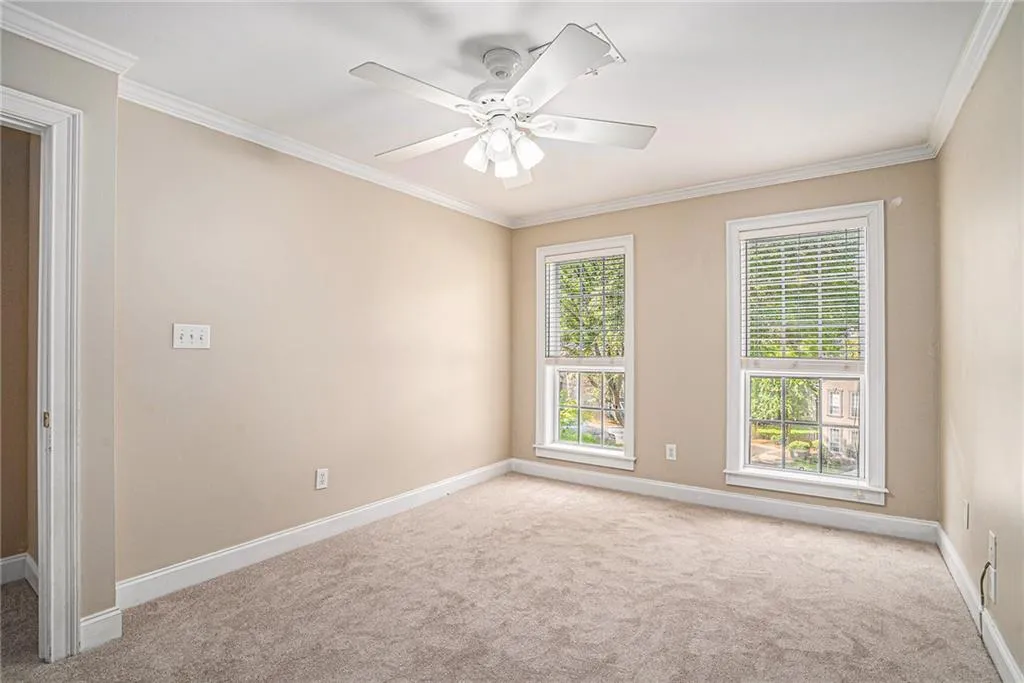 Carpeted empty room featuring ceiling fan and crown molding