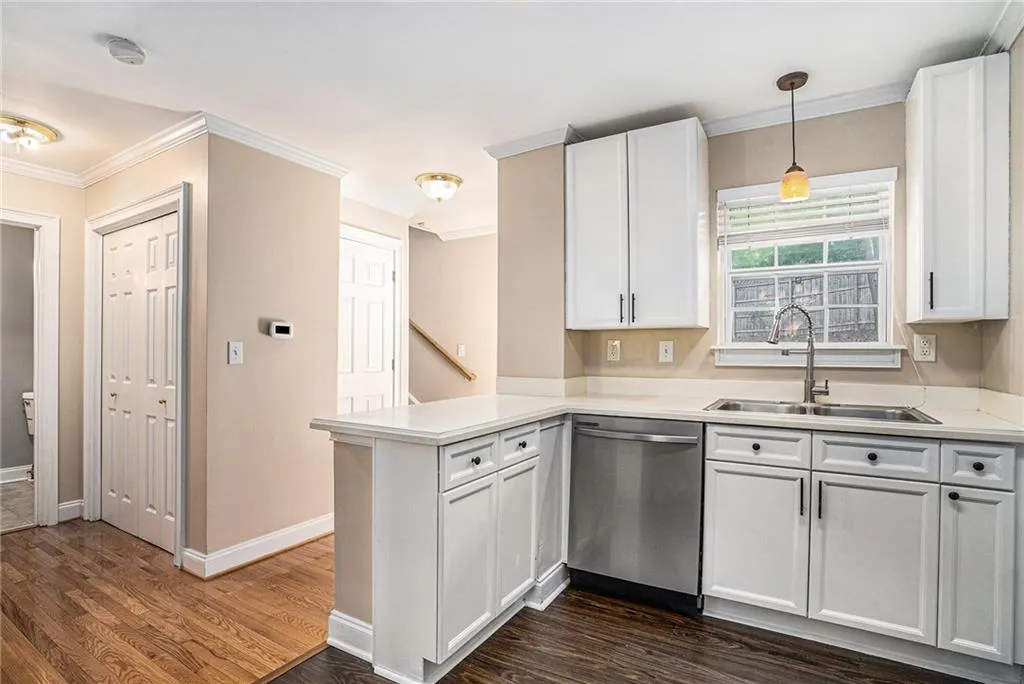 Kitchen with white cabinets, sink, kitchen peninsula, dishwasher, and dark hardwood / wood-style flooring