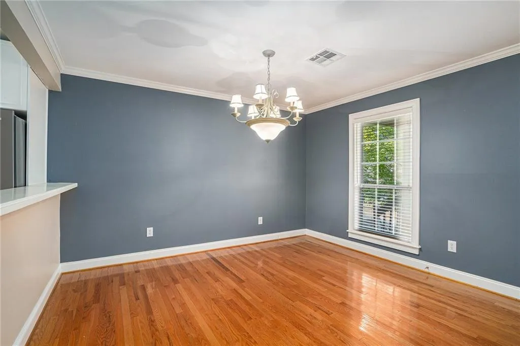 Spare room with crown molding, a notable chandelier, and light hardwood / wood-style flooring