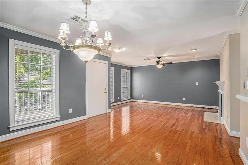Unfurnished room featuring hardwood / wood-style flooring, ceiling fan with notable chandelier, and ornamental molding