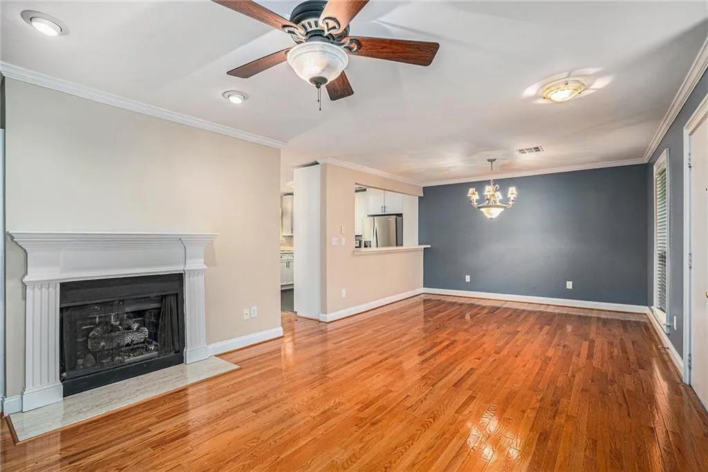 Unfurnished living room with crown molding, ceiling fan with notable chandelier, and wood-type flooring