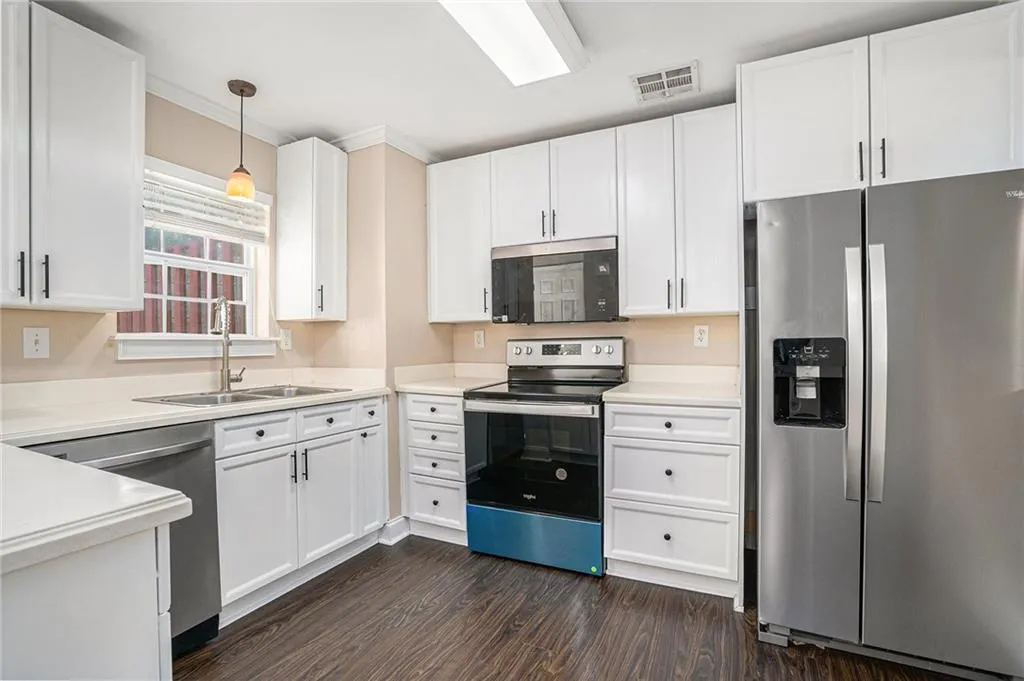 Kitchen featuring dark wood-type flooring, sink, white cabinetry, and stainless steel appliances
