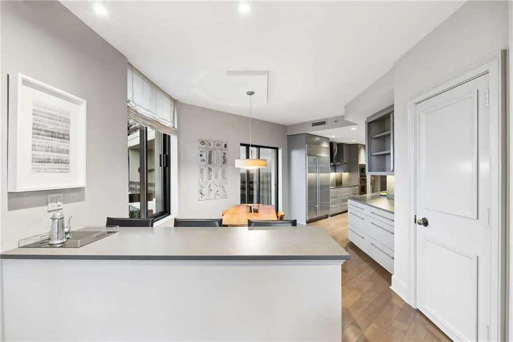Kitchen with a peninsula, built in fridge, light wood-style flooring, decorative light fixtures, and light countertops