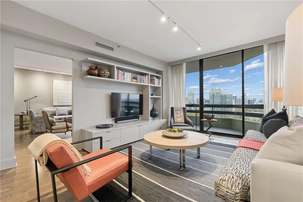 Living area with rail lighting, wood finished floors, and floor to ceiling windows