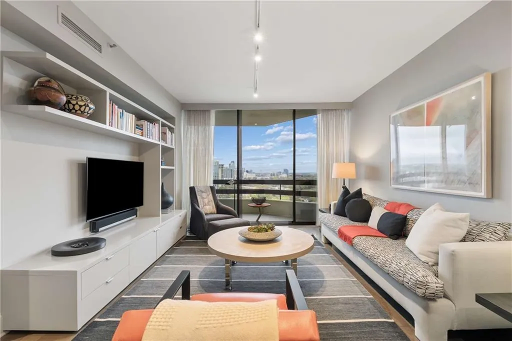 Living area featuring floor to ceiling windows, wood finished floors, and rail lighting