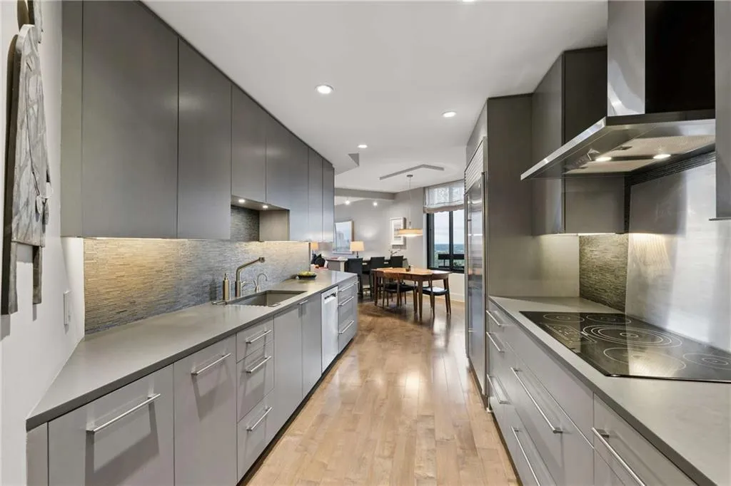 Kitchen with light wood-style floors, stainless steel appliances, light countertops, modern cabinets, and tasteful backsplash