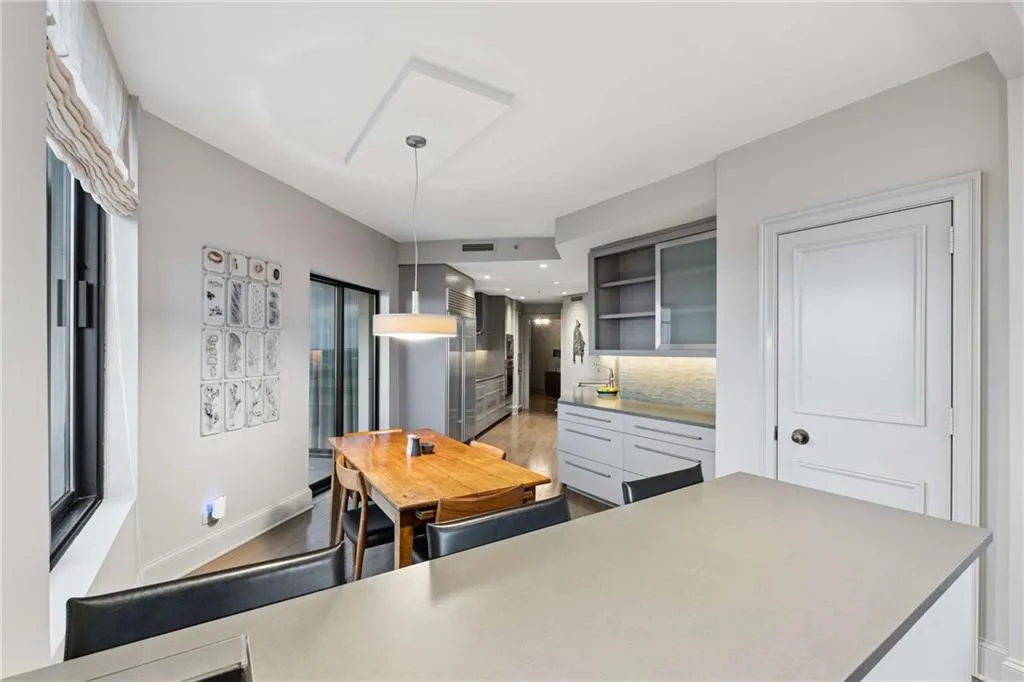 Kitchen with glass fronted cabinets, tasteful backsplash, light countertops, hanging light fixtures, and stainless steel built in fridge