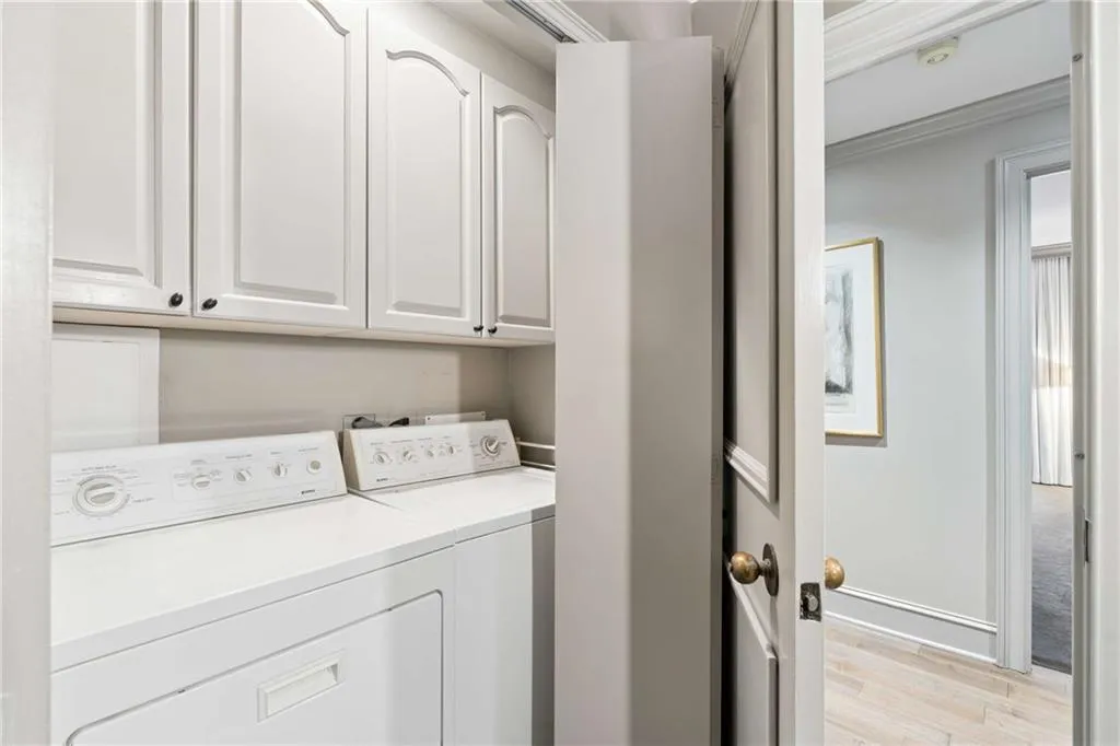 Laundry area featuring cabinet space, light wood-type flooring, separate washer and dryer, and ornamental molding