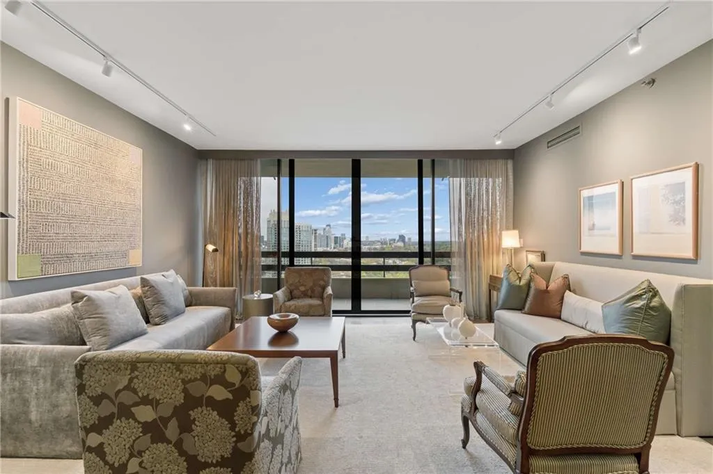 Living room featuring rail lighting, floor to ceiling windows, a view of skyline, and carpet