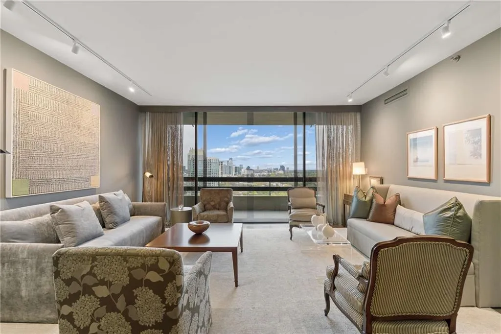Carpeted living room featuring track lighting, a skyline view, and expansive windows