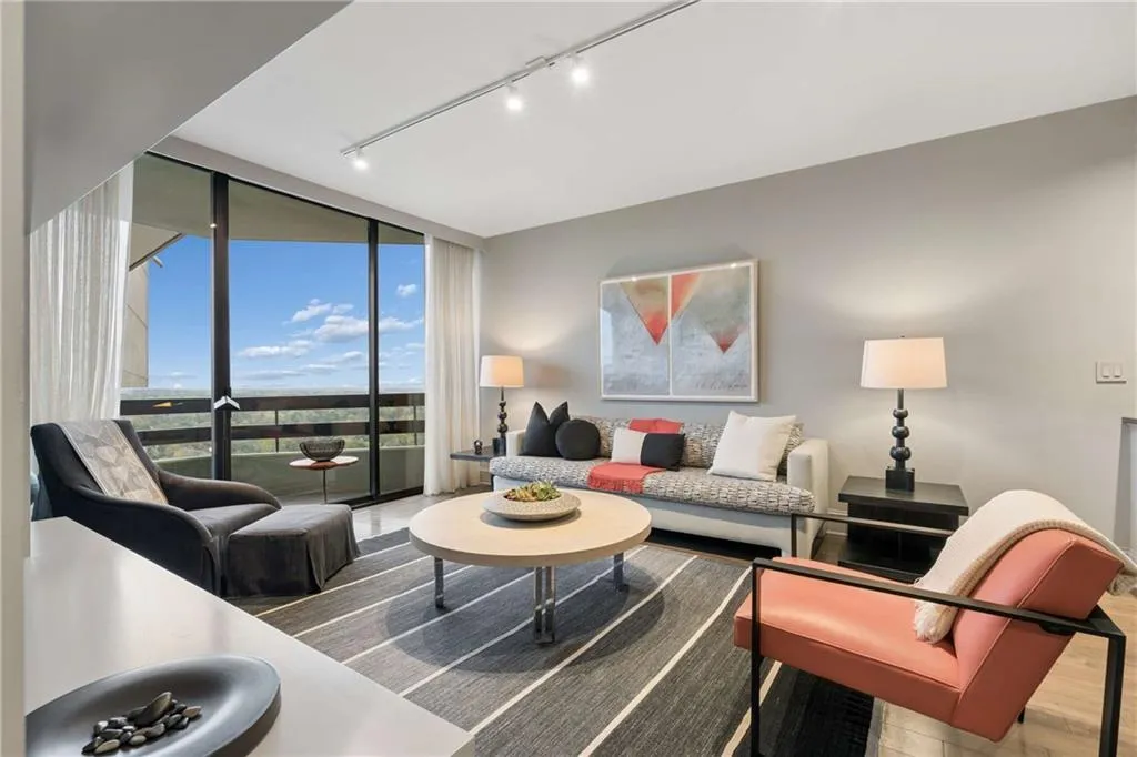 Living room with rail lighting, floor to ceiling windows, and wood finished floors