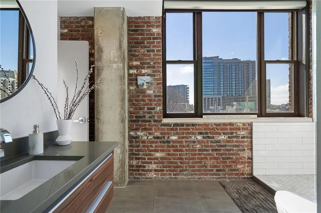 Bathroom with brick wall, a healthy amount of sunlight, and tile patterned floors