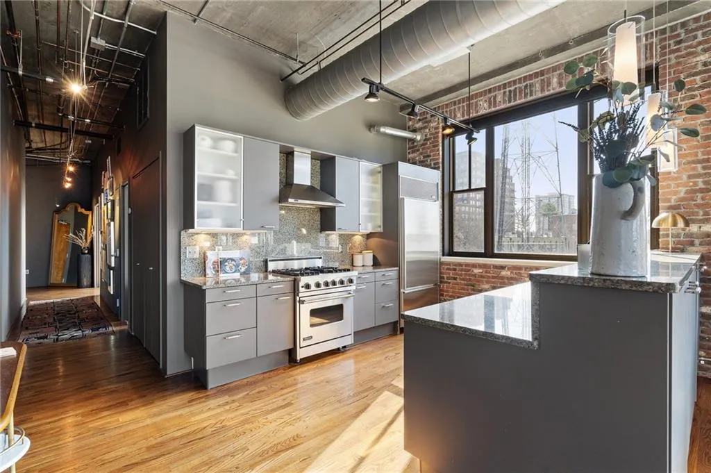 Kitchen with brick wall, a high ceiling, luxury stove, light hardwood / wood-style floors, and wall chimney range hood