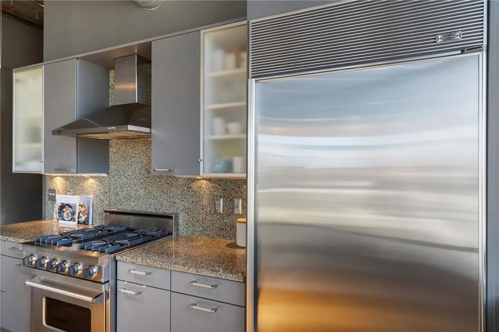 Kitchen featuring wall chimney exhaust hood, appliances with stainless steel finishes, backsplash, and gray cabinetry