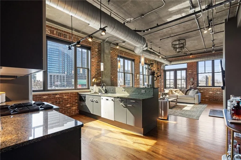Kitchen featuring brick wall, dishwasher, stainless steel gas stovetop, and light wood-type flooring