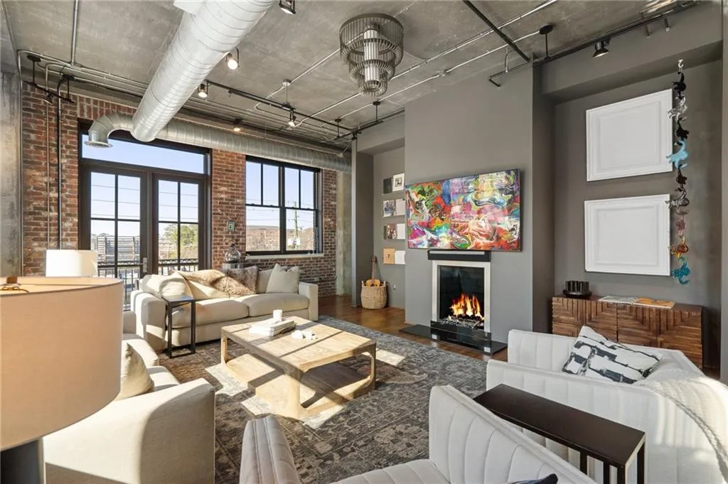 Living room with hardwood / wood-style flooring, brick wall, rail lighting, and a high ceiling
