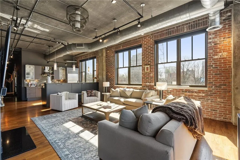 Living room featuring brick wall, dark hardwood / wood-style floors, and rail lighting