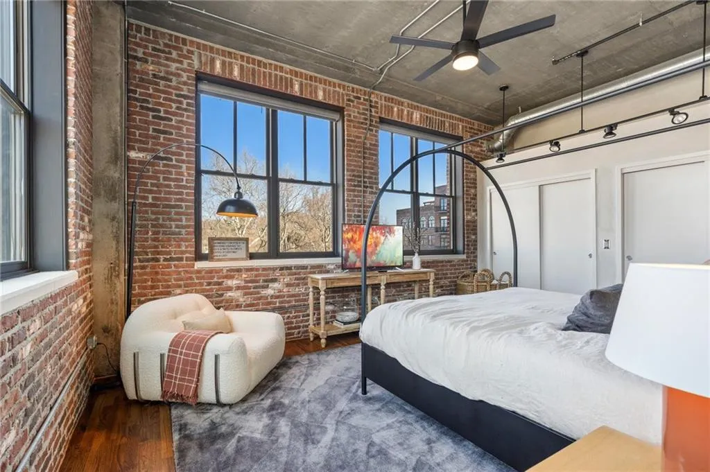 Bedroom featuring a high ceiling, wood-type flooring, and brick wall