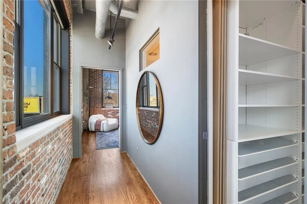 Corridor with hardwood / wood-style flooring, brick wall, and plenty of natural light