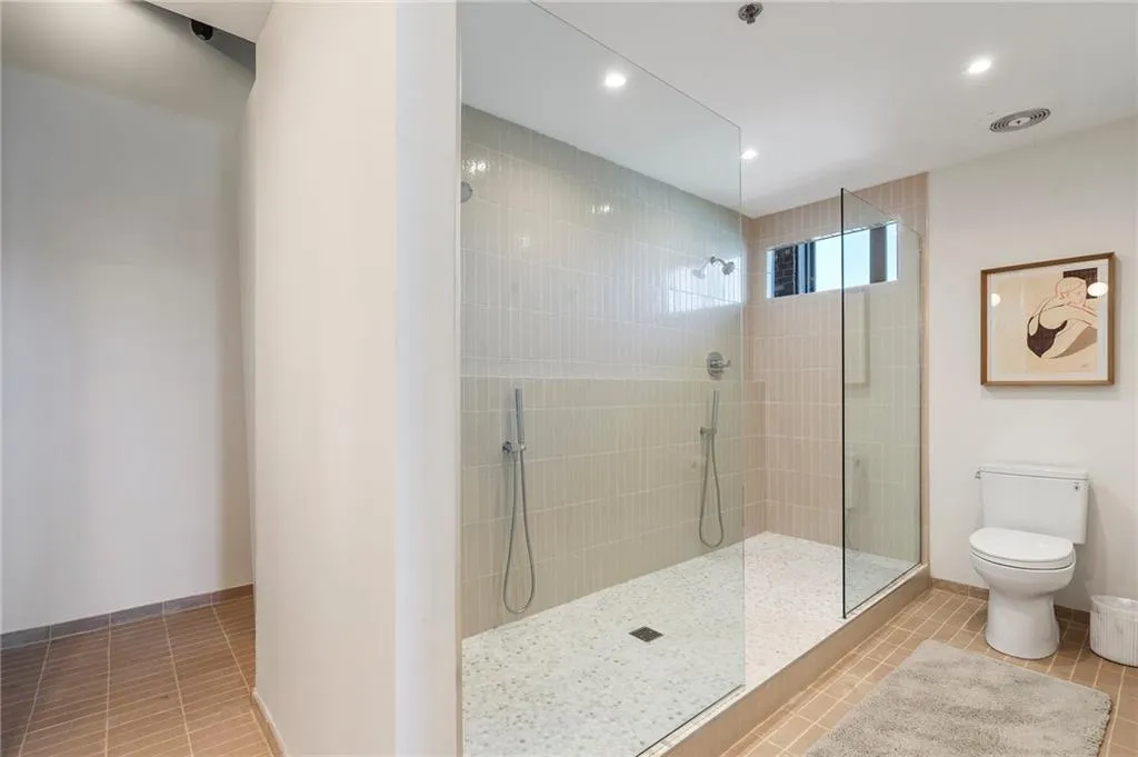 Bathroom featuring tiled shower, toilet, and tile patterned flooring