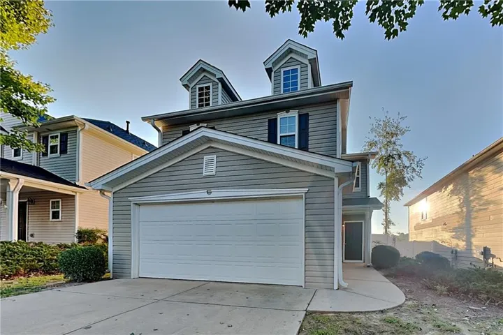 Two-story residence featuring dormer windows, a single-car garage, and a concrete driveway