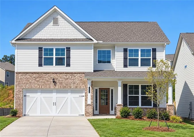 Quick Move In-Brick and siding exterior featuring a covered front entry with columns, attached two-car garage, and mature landscaping