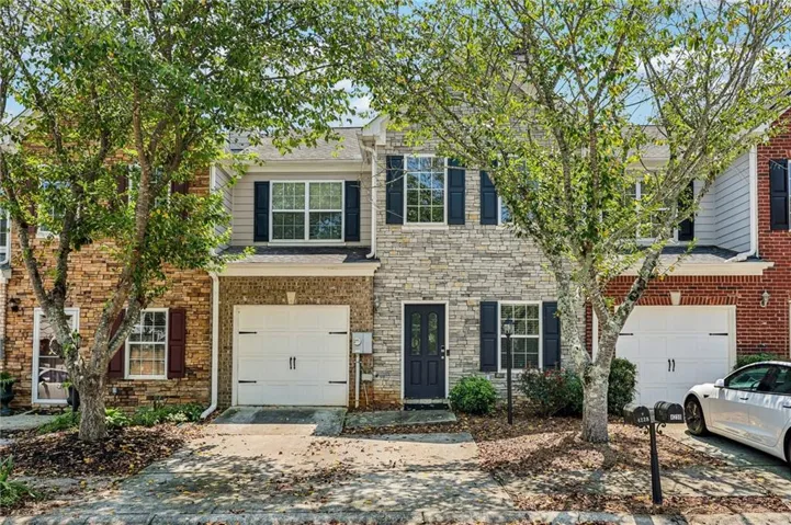 Exterior featuring stone and brick accents, black shutters, a dark entry door, and an integrated garage