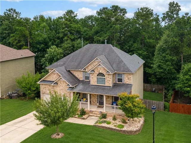 Brick facade home with a covered front porch, arched window, and attached garage