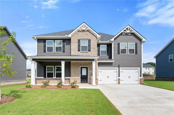 Two-story residence featuring a brick and siding exterior, a covered front porch, and a two-car garage