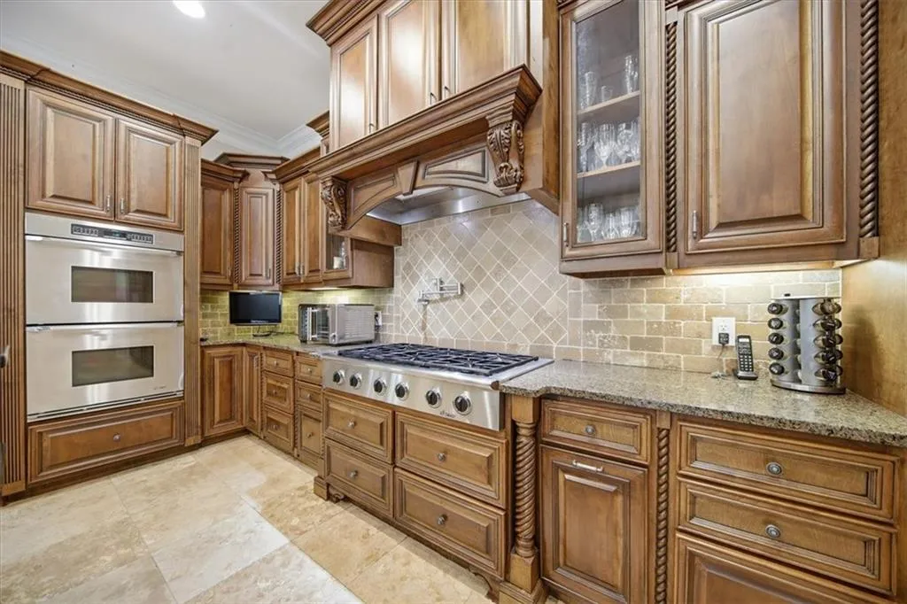 Kitchen with double ovens, pot filler, gas cooktop and granite countertops.