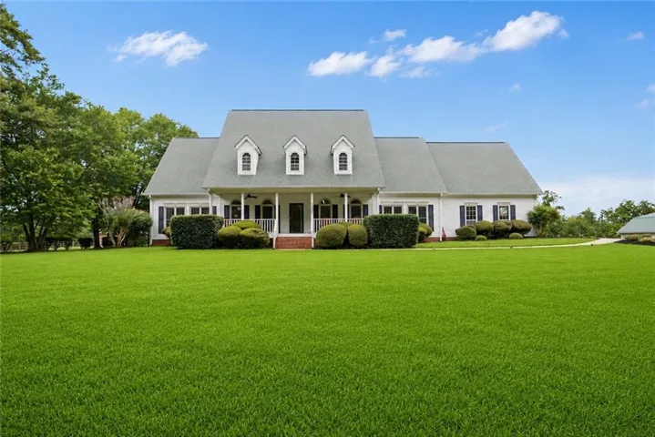 White siding exterior with a prominent front porch, dark shutters, and a dormer roofline