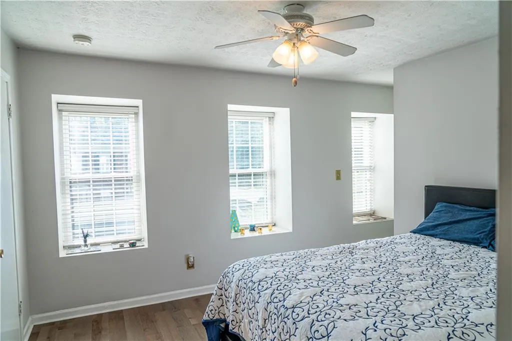 Bedroom with a textured ceiling, wood finished floors, and ceiling fan
