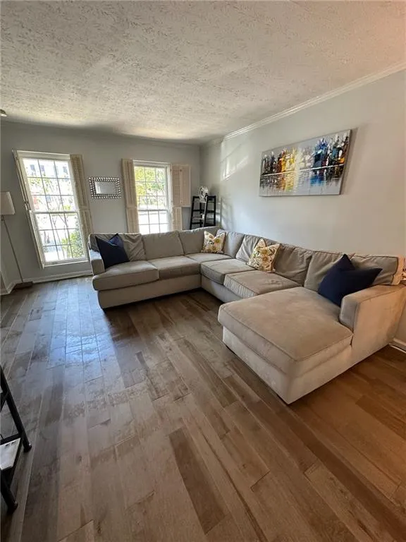 Living area with hardwood / wood-style flooring, a textured ceiling, and ornamental molding