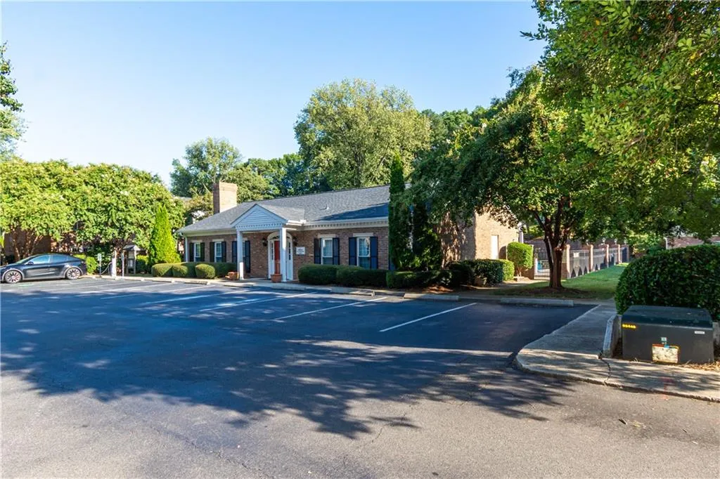 Neoclassical / greek revival house featuring uncovered parking, a chimney, and brick siding