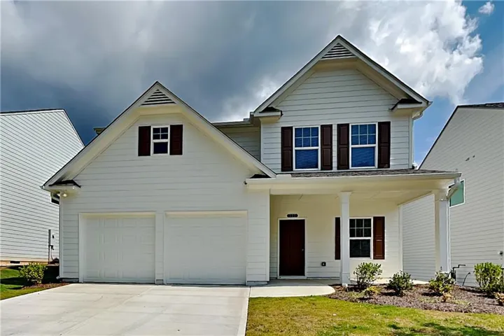 Two-story exterior with white siding, a two-car garage, and dark brown window shutters