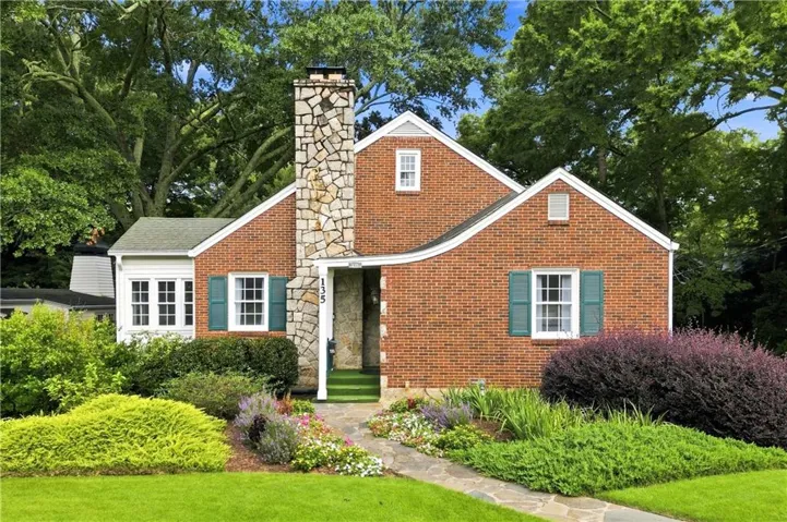 Brick exterior featuring a prominent stone chimney, gabled rooflines, and decorative window shutters