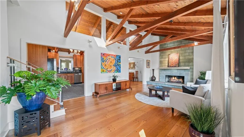Living room with light hardwood / wood-style floors, wooden ceiling, a large fireplace, high vaulted ceiling, and beam ceiling