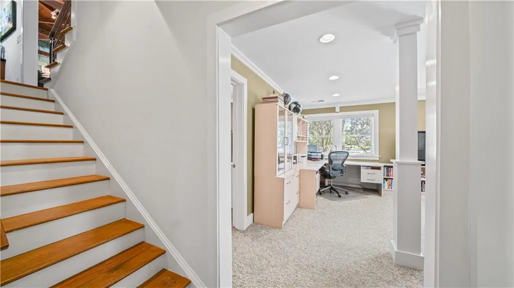 Staircase with ornamental molding, light colored carpet, and built in desk