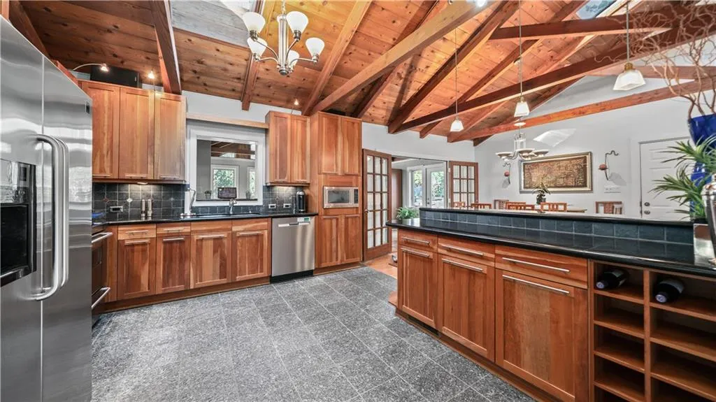Kitchen featuring backsplash, wooden ceiling, dark tile floors, beamed ceiling, and appliances with stainless steel finishes
