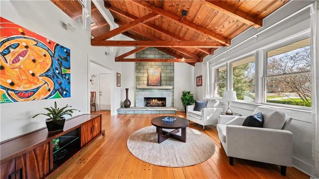 Living room featuring wood ceiling, light hardwood / wood-style flooring, vaulted ceiling with beams, and a fireplace