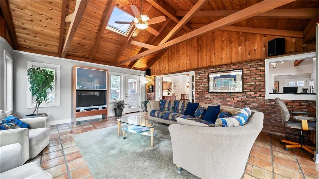 Tiled living room with brick wall, wood ceiling, beamed ceiling, and a skylight